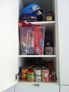 Crisps coralled in big box. Cans occupy the shelf below.